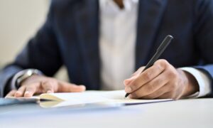 Business man executive wearing suit writing in notebook or legal document. Business man executive wearing suit writing in notebook or legal document.
